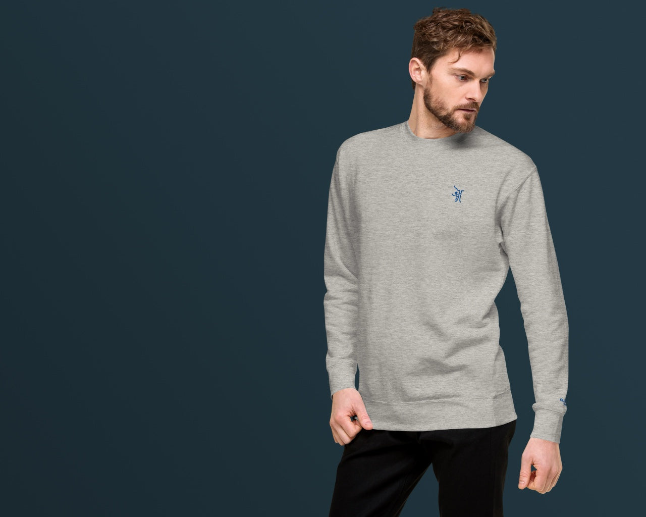 OT Essential Autumn Pullover, Vorderansicht männliches Model trägt simplen Grauer Pullover, Model auf rechter Seite mit dunkelblauem Hintergrund